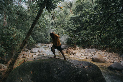 Rear view of man on rock in forest