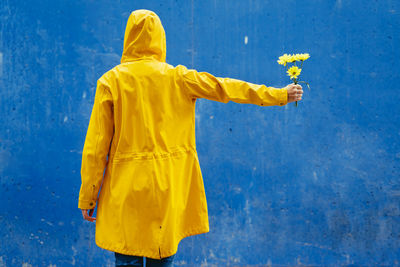 Rear view of woman standing against blue wall