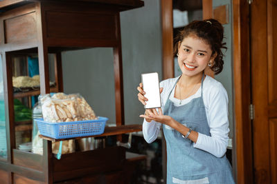 Portrait of smiling young woman holding food at home