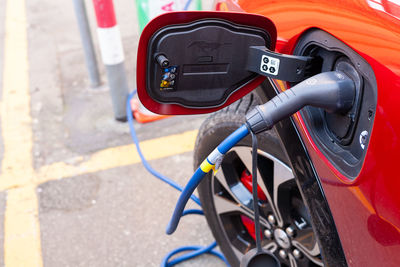 A cable is recharging an electric car at the charging station