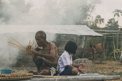 Man making wicker basket while girl studying