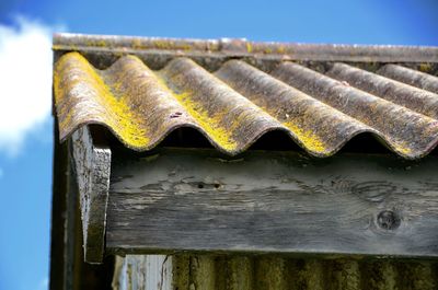 Close-up of rusty metallic roof against blue sky