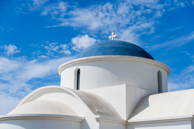 Low angle view of white church with blue roof against blue cloudy sky