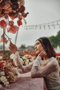 Woman looking at flowering plants against sky