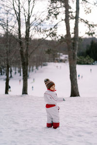 Rear view of woman standing on snow covered field