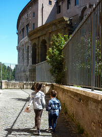 Two children walking in the historic center of rome. the little girl guides her younger brother. 