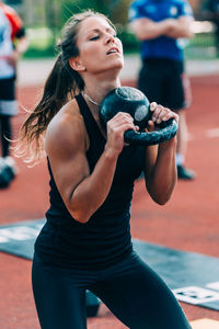 Woman lifting kettlebell on running track