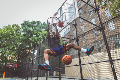 Low angle view of man jumping against basketball hoop