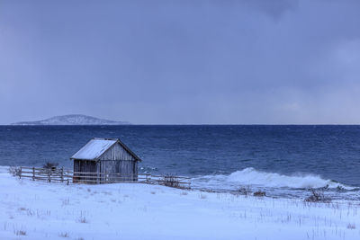 House by sea against sky during winter