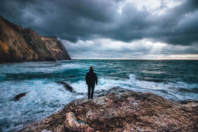 Rear view of man looking at sea against sky