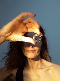 Close-up of woman holding diamond in front of face