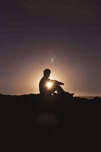 Silhouette of man on mountain against clear sky at sunset