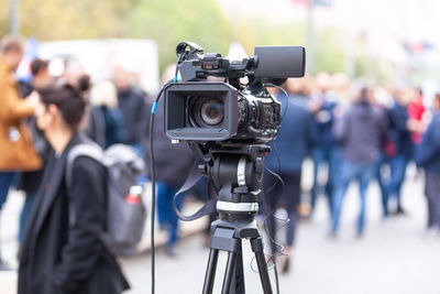 Tv camera lens in the focus, blurred people in the background