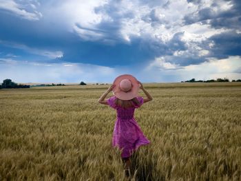 Rear view of woman standing on field against sky