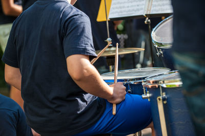 Midsection of man playing drum on stage