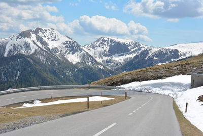 Road by snowcapped mountains against sky