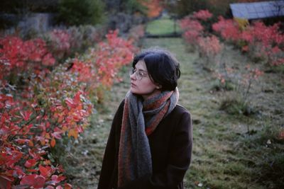 Young woman standing against plants