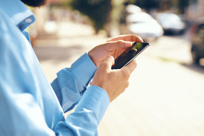 Midsection of man holding mobile phone