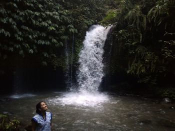 Full length of waterfall on rocks in forest