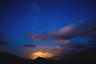 Scenic view of silhouette mountains against star field