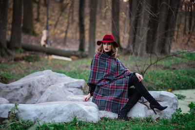 Portrait of woman sitting on field in forest