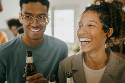 Cheerful young man and woman with beer bottles in kitchen