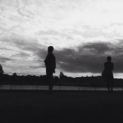 Silhouette people standing against cloudy sky