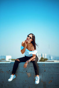 Young woman wearing sunglasses against clear blue sky