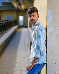 Portrait of young man standing against wall