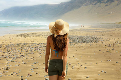 Rear view of young woman walking on beach