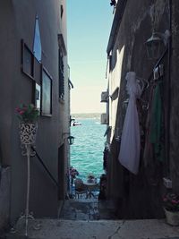 Houses by sea against clear blue sky