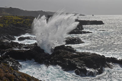 Waves splashing on shore against sky