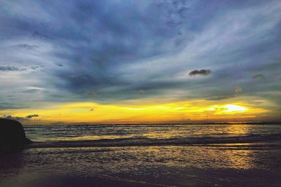 Scenic view of sea against dramatic sky during sunset