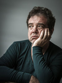 Depressed man looking away against gray background