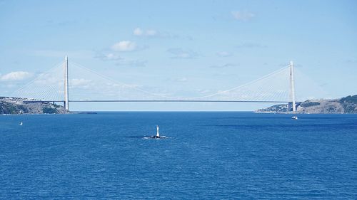 Scenic view of suspension bridge over sea against sky