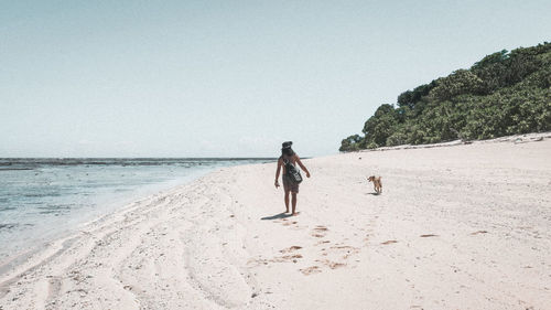 People walking on beach against clear sky