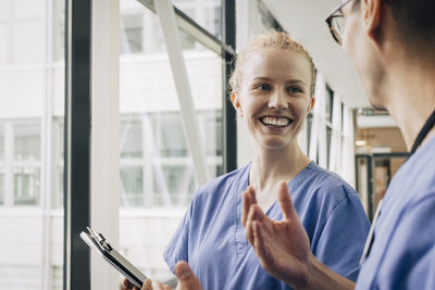 Happy young female nurse discussing with male colleague at hospital