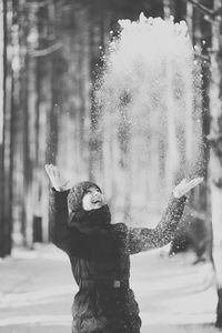 Young woman standing by tree in forest during winter