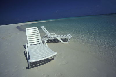 White lounge chairs at shore