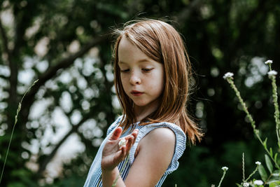 Young girl looking down at a small white flower in her hand