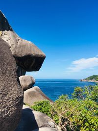 Scenic view of rocks by sea against blue sky