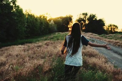 Rear view of woman standing on grassy field