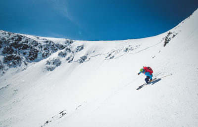 Person skiing on snowcapped mountain against sky