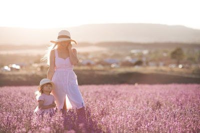 Mother and daughter standing on flower field