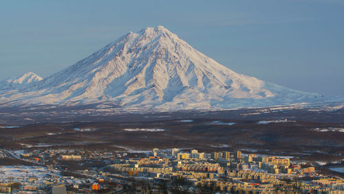 Aerial view of city by mountain against sky