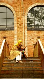 Full length of woman sitting on staircase