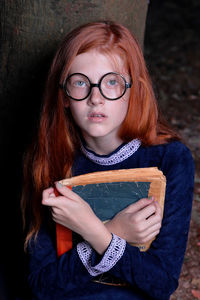 Portrait of cute girl holding book while sitting at home