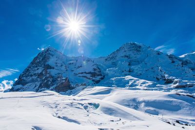 Scenic view of snowcapped mountains against blue sky on sunny day