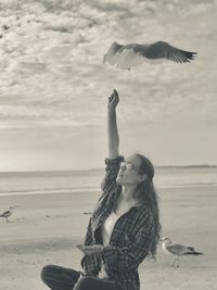 Woman holding umbrella on beach against sea