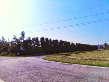 Road amidst trees on field against clear sky